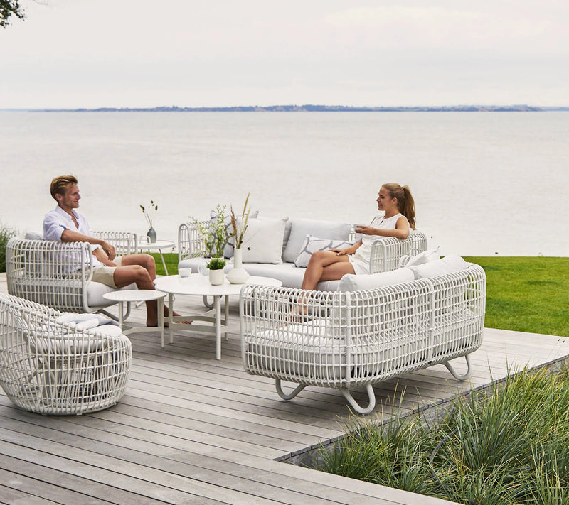 Couple sitting on white outdoor furniture on deck by the ocean