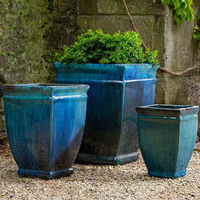 Grouping of 3 blue containers in front of stone wall