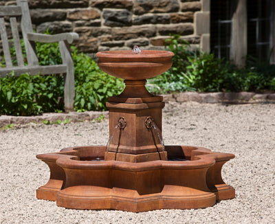 Brown fountain with small basin placed on a decorative pedestal, water pouring into quatrefoil basin