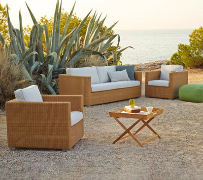 Deep seating set shown on gravel patio and ocean in the background