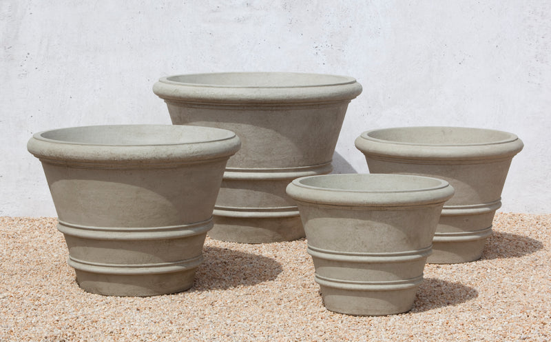 Grouping of 4 cast stone containers in different sized shown on gravel