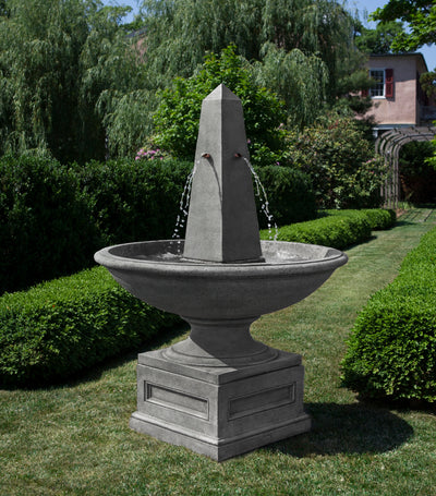Large bowl fountain with obelisk accent in the middle pictured on lawn