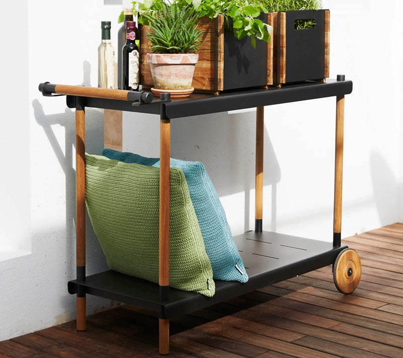 Black trolley with blue and green cushions  against a white wall