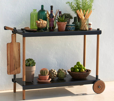 Black trolley with food and plants against wall
