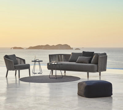 Grey outdoor furniture set on a light terrace by a body of water