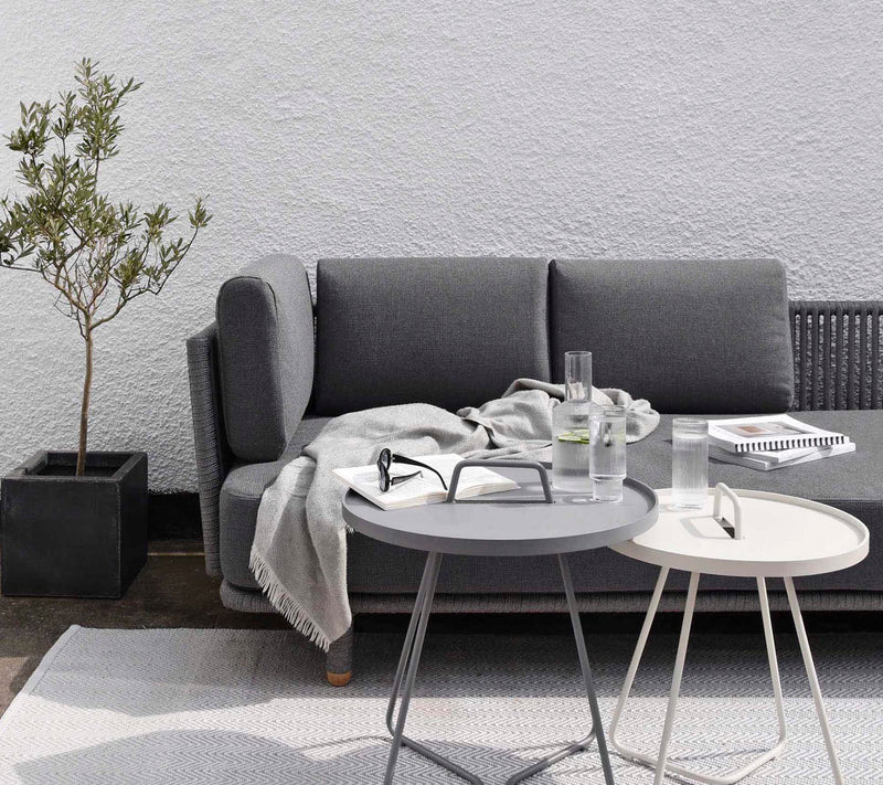 Grey sofa with two side tables in front of a light grey wall