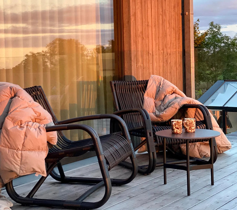 Two black armchairs with salmon throw blankets on their arms in front of large glass wall