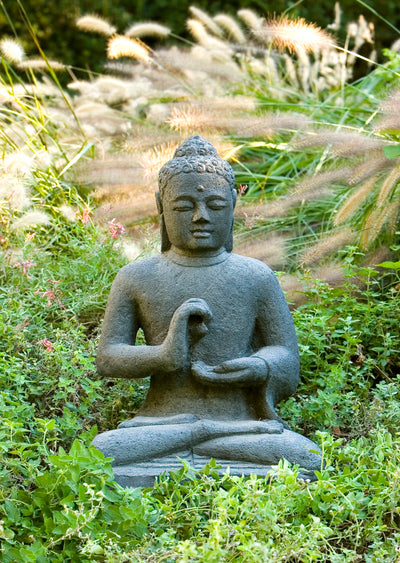 Sitting dark gray buddha in the middle of greenery