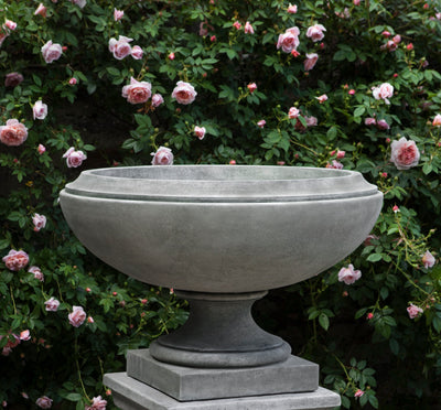 Grey  urn shown in front of pink roses