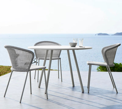 White table and three gray armchairs sitting in front of an ocean view