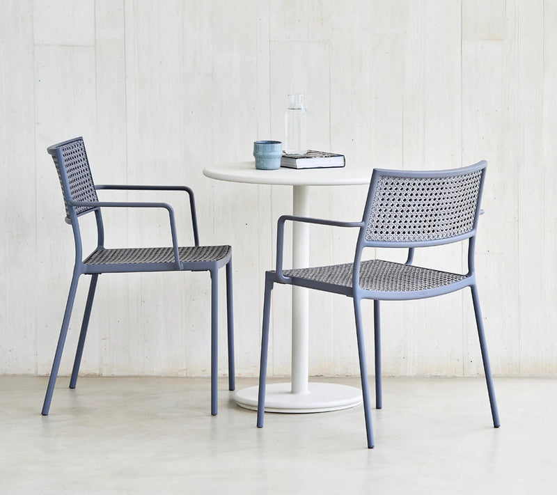 Bistro set with a round white table and two grey chairs against white wall