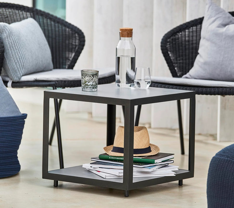 Square coffee table with glasses and a hat on lower level