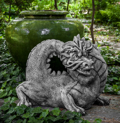 Gray dragon with tail curved back to head in front of green pot