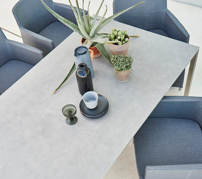Top view of rectangular table with four dark grey armchairs and potted succulents