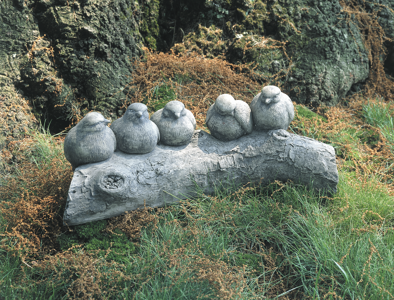 Five light gray birds sitting on a tree log in grass