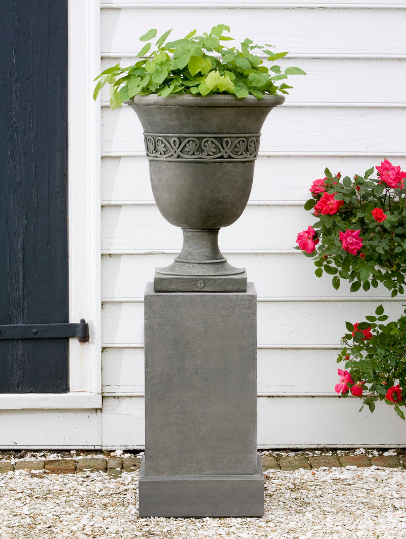 Strapwork urn shown planted with greenery and standing on a pedestal