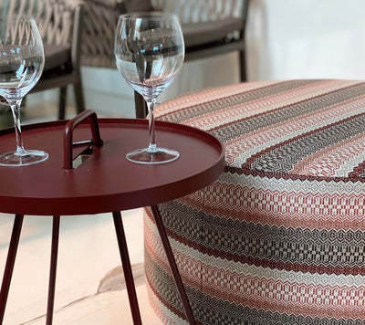Burgundy coffee table with two glasses next to a sitting cushion