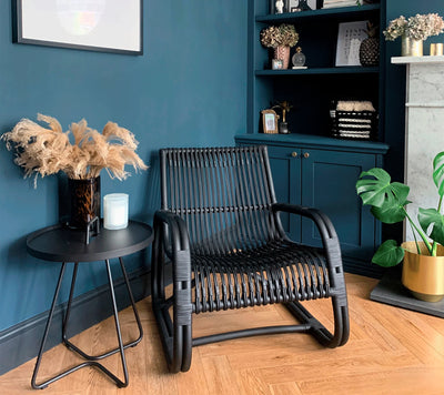 Black armchair next to a black coffee table in front of blue wall