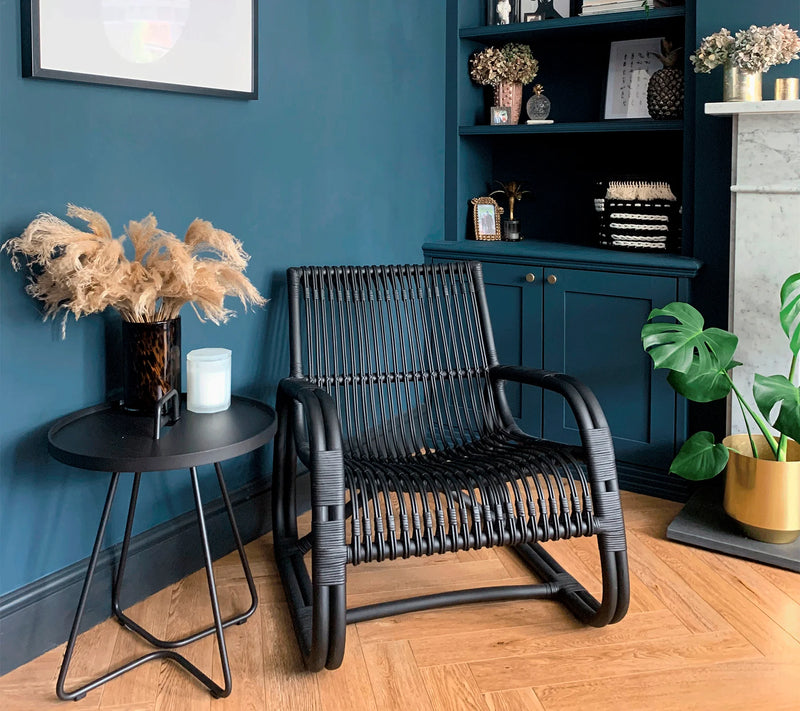 Black armchair next to a black coffee table in front of blue wall