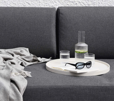 Tray with glassware shown on dark gray couch and a throw blanket