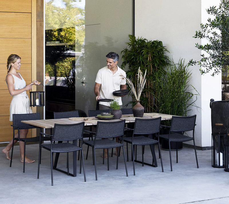 A couple setting an outdoor dining table in front of house wall