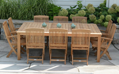 Rectangular teak  table with ten chairs in front of greenery
