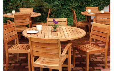Three sets of teak dining tables and chairs on brick patio