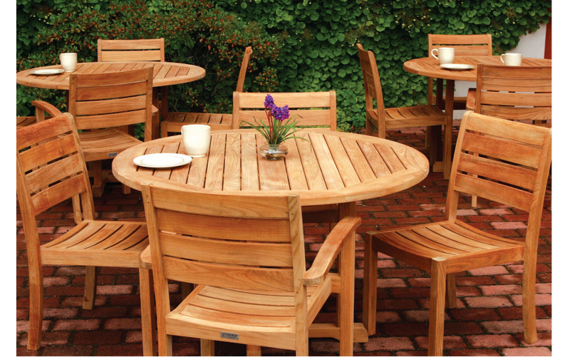 Three sets of teak dining tables and chairs on brick patio
