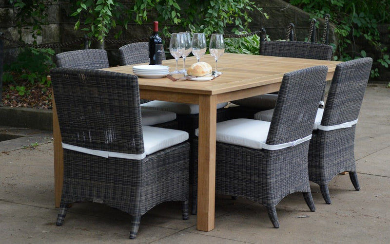 Teak table with black chairs shown with wine glasses and bottle on the table