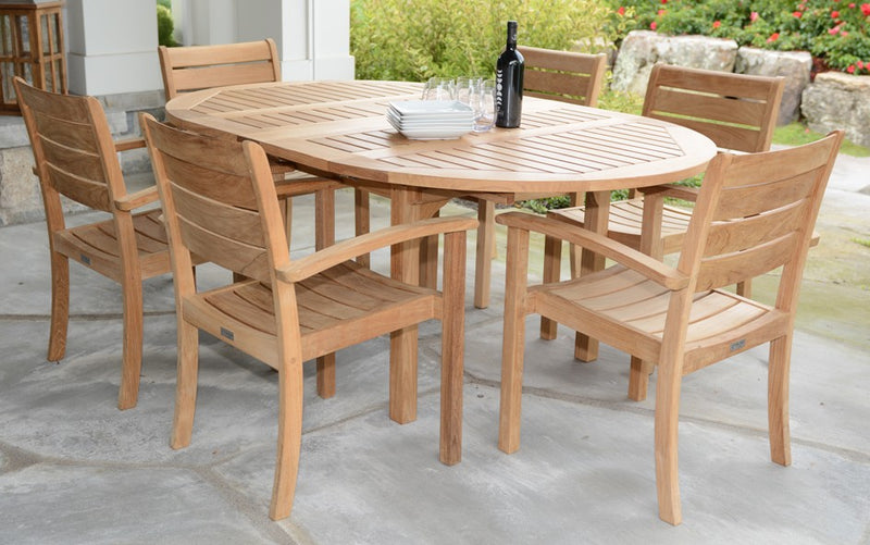 Extended round teak table shown with six chairs and bottle of wine