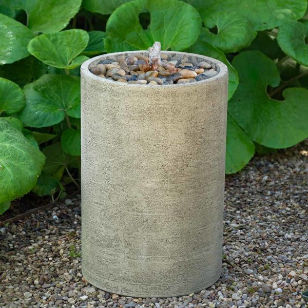 Tall round column fountain with gravel on top of circular top and copper spout pictured on gravel