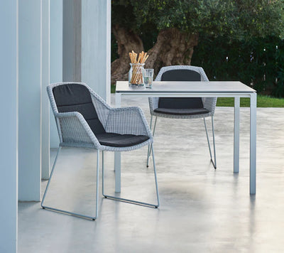 Dining set with one table and two armchairs on white patio with  breadsticks on table