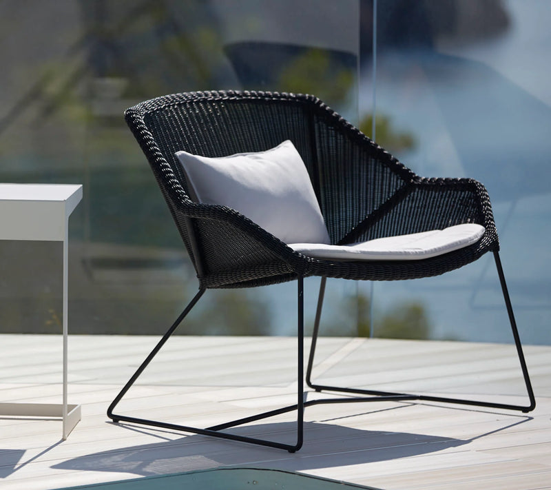 Contemporary black woven outdoor chair with white cushions