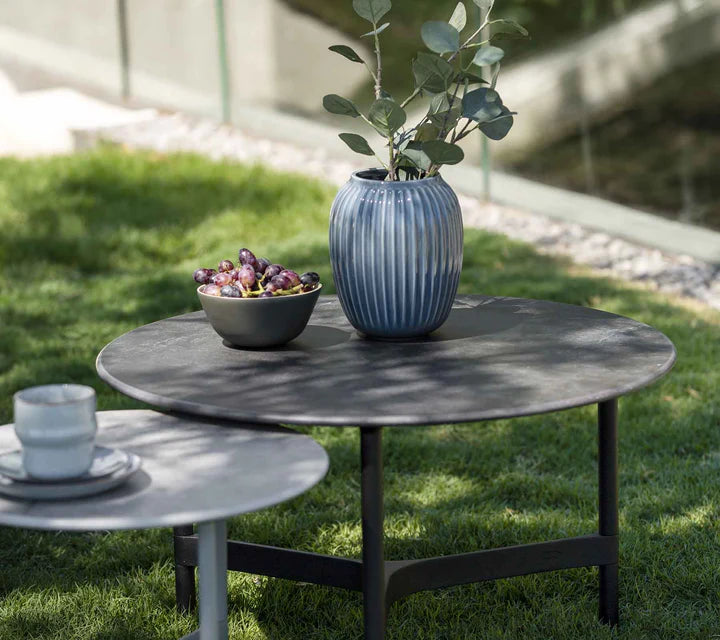 Two coffee tables on grass with bowl of grapes