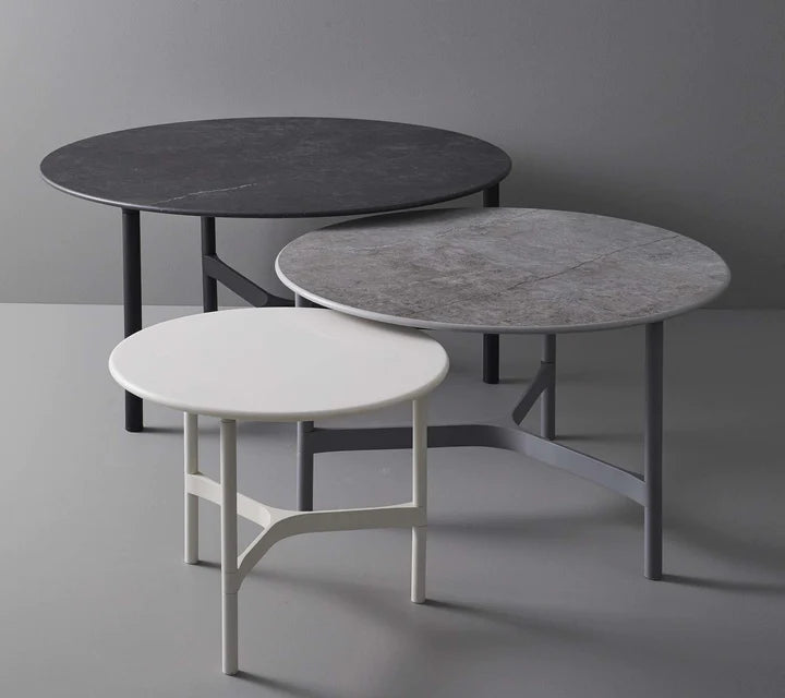 Black, gray and white coffee tables in different sizes on gray background