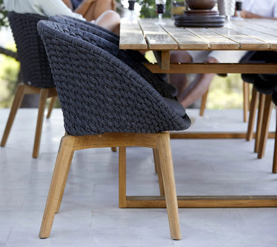 Black woven chair with wooden legs pushed under a table