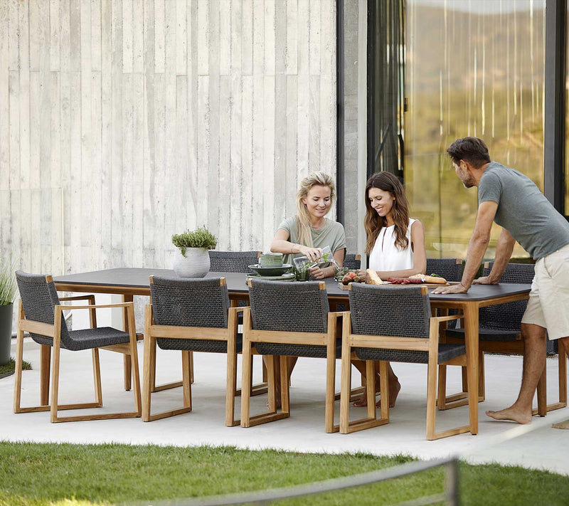 Rectangular dining table with eight chairs and three people talking