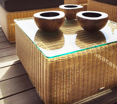 Woven outdoor coffee table and footstool with glass top and three wooden bowls