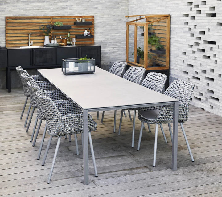 Grey dining set on grey wooden deck in front of white wall