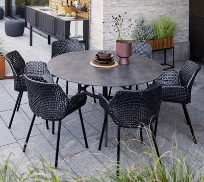 Round table dining set with kitchen in the background and grasses in the foreground