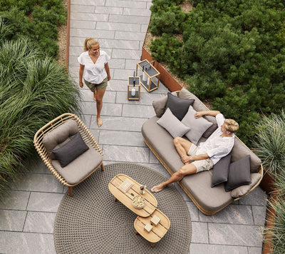Top view of outdoor seating area with one man sitting on sofa and one woman walking towards him
