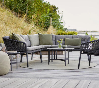 Outdoor gray furniture shown on gray decking and grasses on the sides