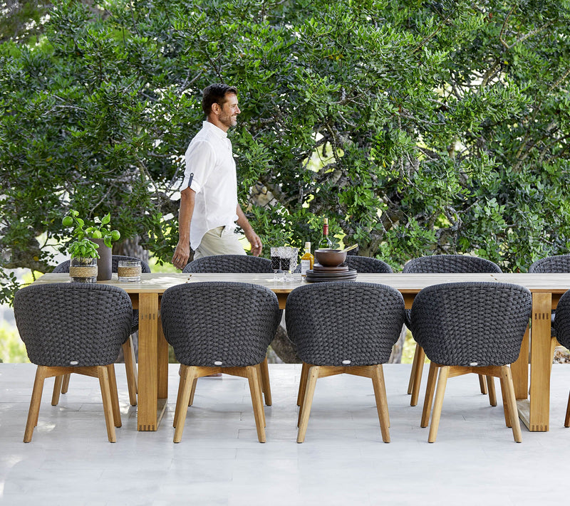 Man walking between a dining set and trees 