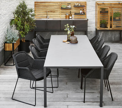 Rectangular gray table with eight chairs shown in front of outdoor kitchen