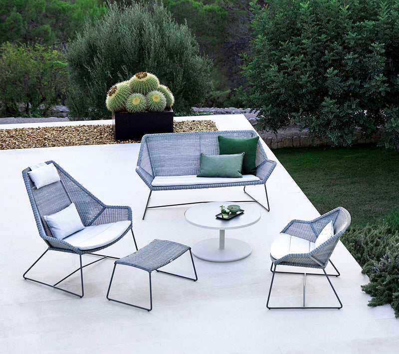 Matching outdoor set of gray woven furniture with white coffee table on white terrace