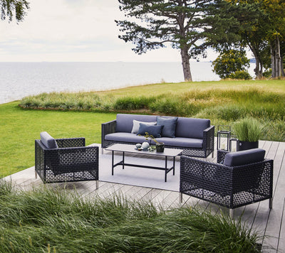 Deep seating set shown on wooden deck with tall grasses in front and ocean views