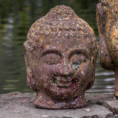 Dark terra cotta color buddha head by water