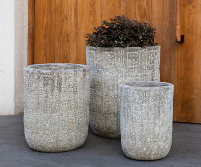 Grouping of 3 grey containers in front of wood pannel