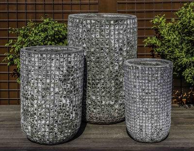 Grouping of 3 tall containers in front of metal fence