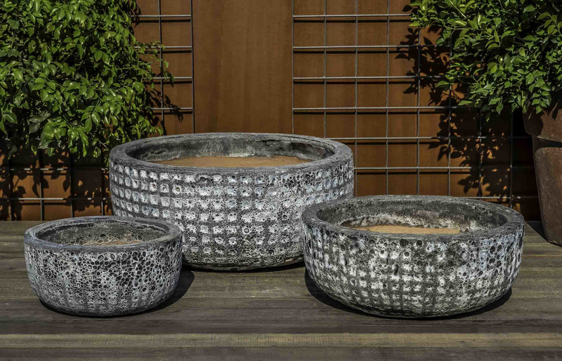 Grouping of 3 low bowls in front of metal fence
